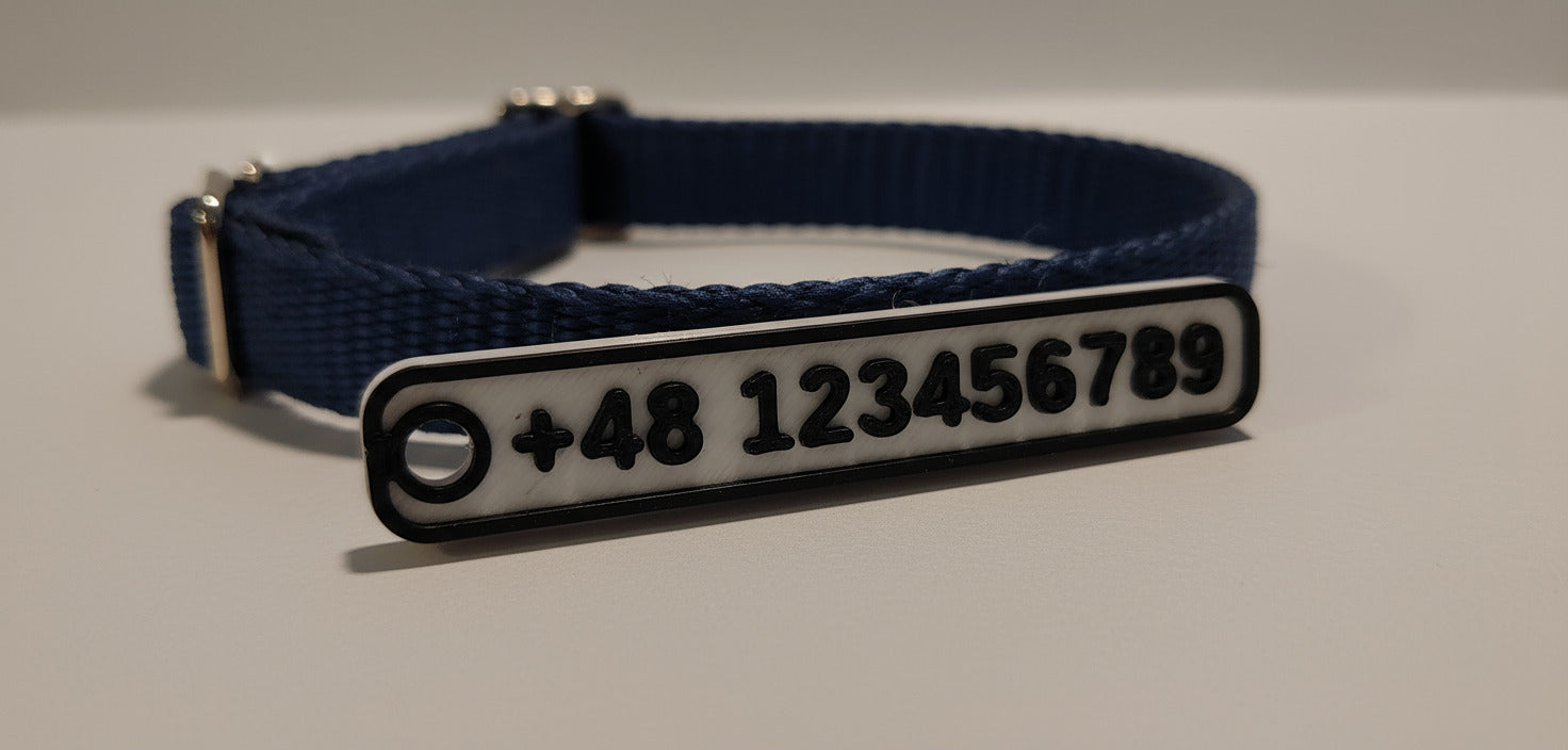 Navy blue dog collar with a metallic tag on a light gray background