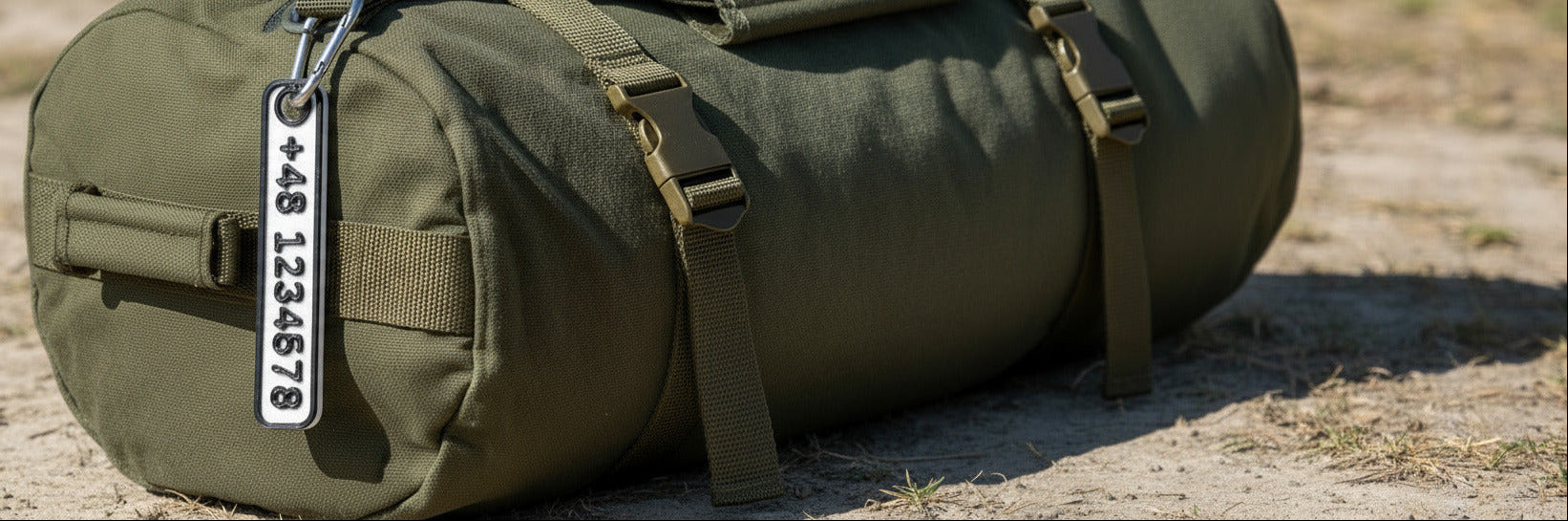 Green duffel bag with a tag on a sandy ground