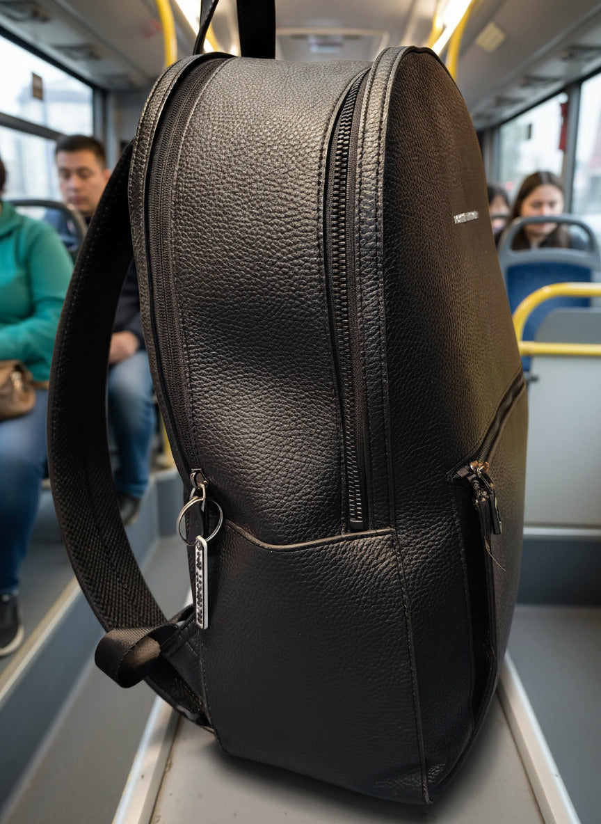 Black leather backpack on a bus seat with people in the background